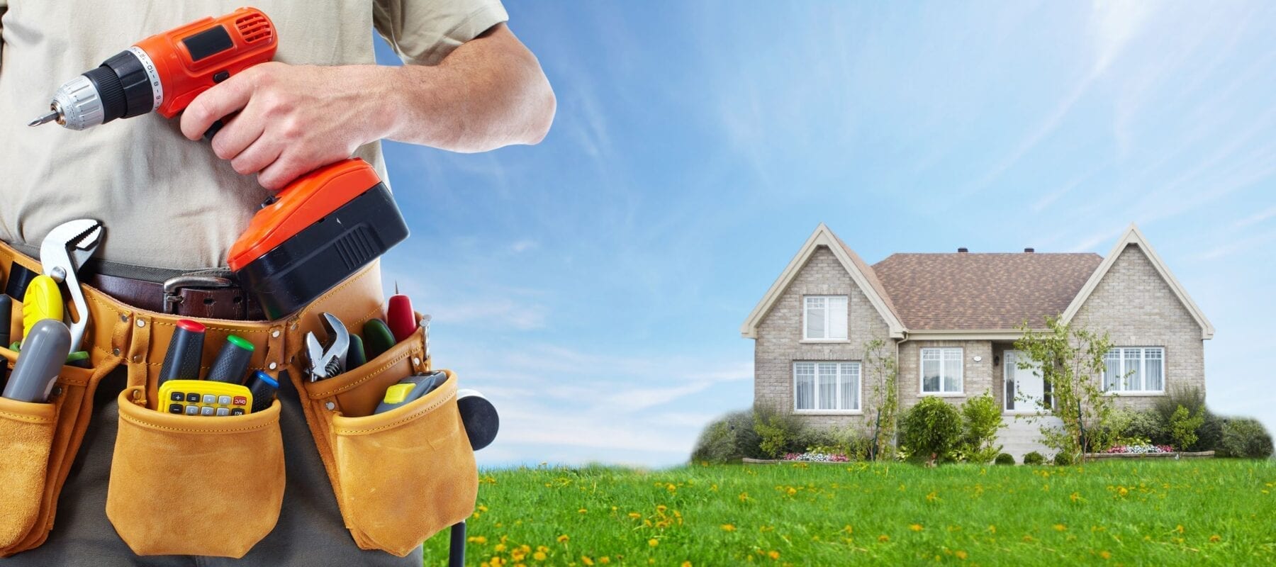 A handyman holds up a power drill while wearing a tool belt. There is a two-story house in the background.