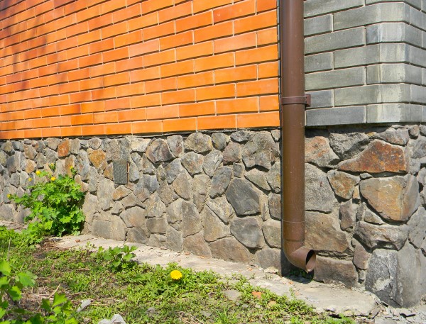 The side of a home that received foundation repair treatment from BDB Waterproofing. The exterior of the home includes rock and brick siding.