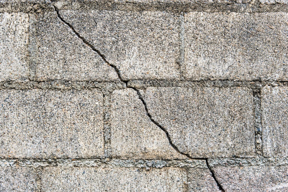 A crack forms in the foundation of this home. The hairline crack runs from the top left corner to the bottom right.