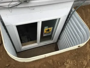 An egress window installation looking at it from the outside. The window is situated in the basement window well.